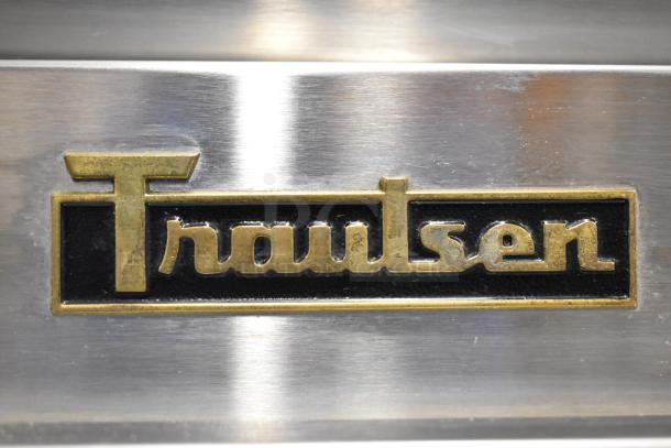 Traulsen G12010 stainless steel logo plate on commercial freezer, indicating high-quality make and model.