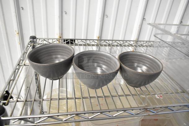 Lot of various items including poly drop-in bins and gray bowls on a metal shelf. Shelving not included.