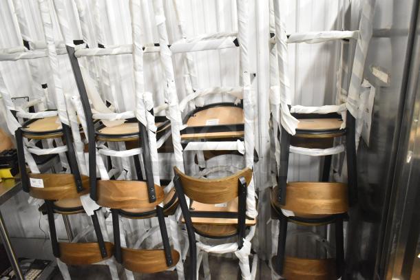 12 new Lancaster Table & Seating black metal bar height chairs with wooden backrests and seats, scratch and dent condition.