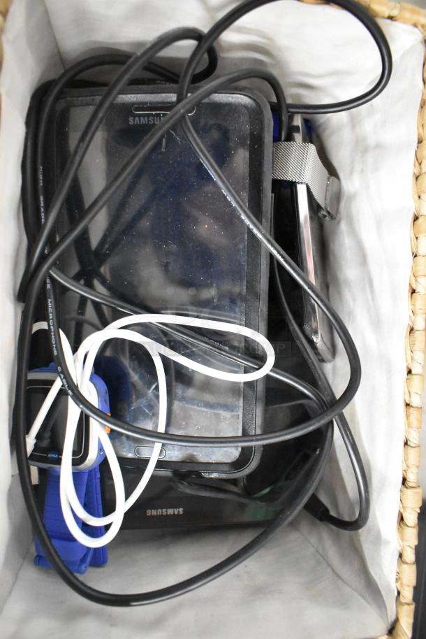 Basket containing 22 various items including Samsung phones, tablet, and tangled charging cables, mixed condition.
