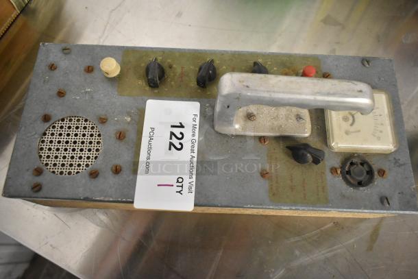 Vintage metal panel with knobs, meter, speaker, and handle. Signs of wear and rust. Auction label "122 QTY 1."