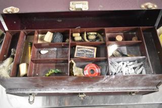 Vintage Kennedy fishing tackle box with assorted contents, including lures, line, weights, and Independence safety matchbox.