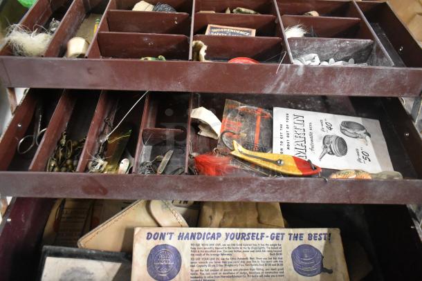 Vintage fishing tackle box filled with lures, hooks, and tools; features multiple compartments and a "Martin Automatic Reel" brochure.