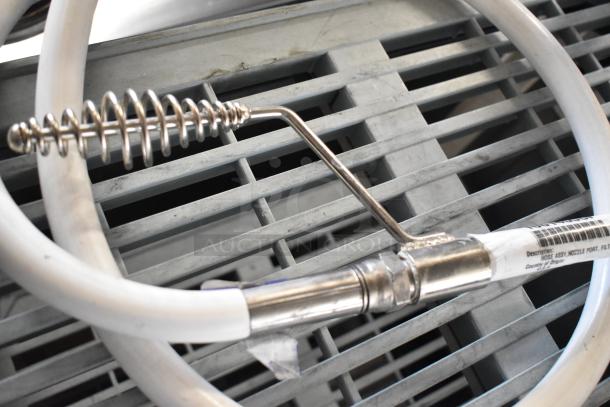 Hose assembly for oil filter with stainless steel fittings and coiled section, shown on a gray slatted surface.