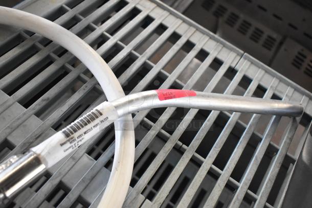 Hose assembly for oil filter, featuring metal connectors and visible barcode label. In good condition, with pink tag marked "1/1 EA ground."