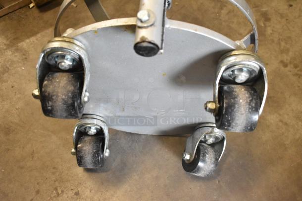 Metal bowl dolly with four commercial casters, showing wear. Made of sturdy metal for transporting heavy items.