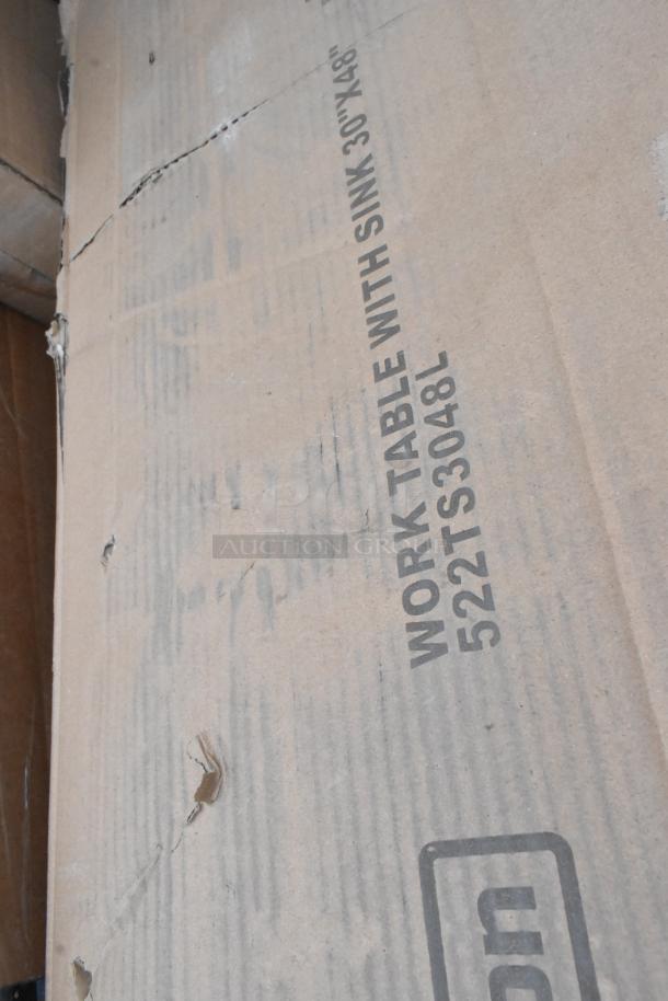 Cardboard box with "WORK TABLE WITH SINK 30'' X 48'' 522TS3048L" label, showing scratches and dents, new condition.