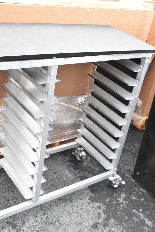 Metal double pan transport rack with 14 slots, commercial casters, and a sturdy top surface. Used condition.