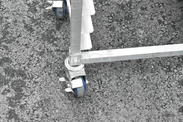 Metal double pan transport rack with commercial casters, showing sturdy construction and smooth-rolling blue wheels.