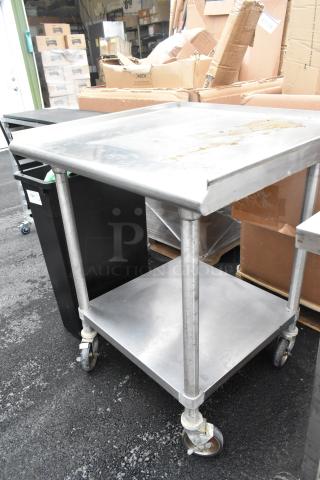 Stainless steel commercial table with metal under shelf, mounted on four heavy-duty commercial casters. Used condition.