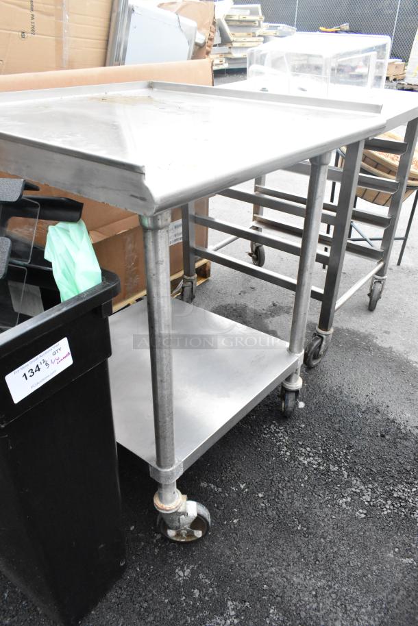 Stainless steel commercial table with metal under shelf on casters, used condition, ideal for kitchen or industrial use.