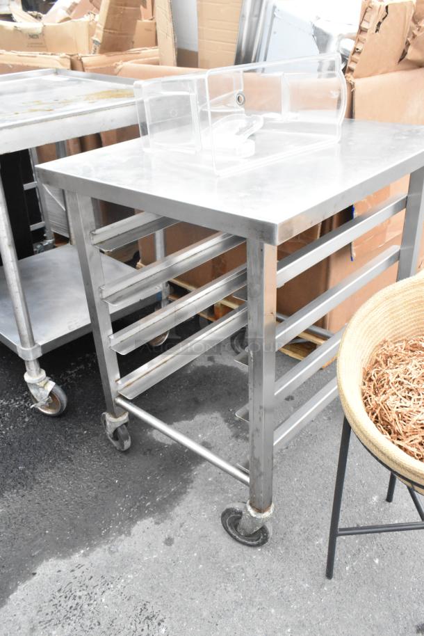 Metal pan transport rack with commercial casters, used condition, multiple shelves, sturdy metal frame.