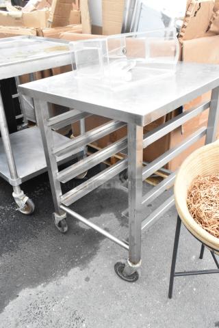 Metal pan transport rack with commercial casters, used condition, multiple shelves, sturdy metal frame.