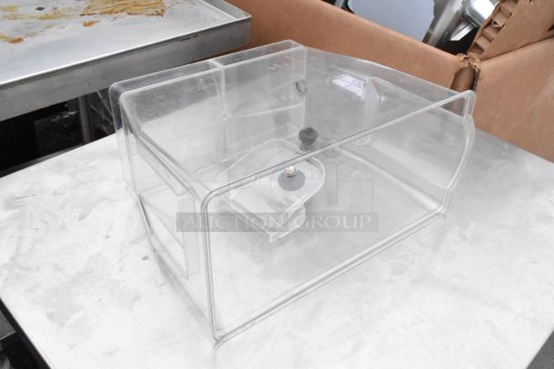 Transparent plastic food cover with black knob handle on stainless steel surface.