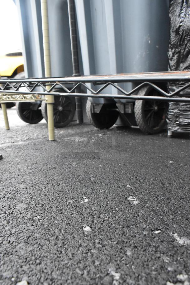 Black finish 4-tier wire shelving unit on asphalt surface. Buyer responsible for dismantling. Consider freight charges.