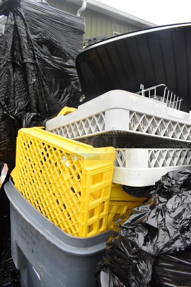 Rubbermaid gray poly trash can filled with yellow and gray caddies, covered by black bags. Appears in used condition.