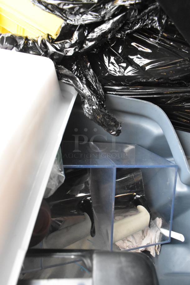 Rubbermaid gray poly trash can with various contents, including a poly bin and black trash bags; suitable for utility use.