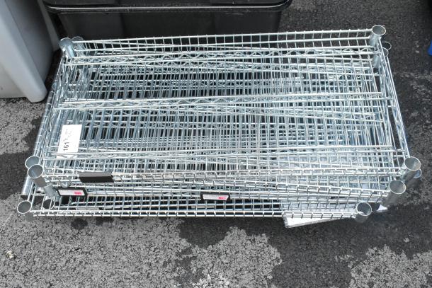 Lot of 11 chrome finish wire shelves, excellent condition, various dimensions, ideal for storage. Visible auction tag.
