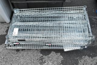 Lot of 11 chrome finish wire shelves, excellent condition, various dimensions, ideal for storage. Visible auction tag.