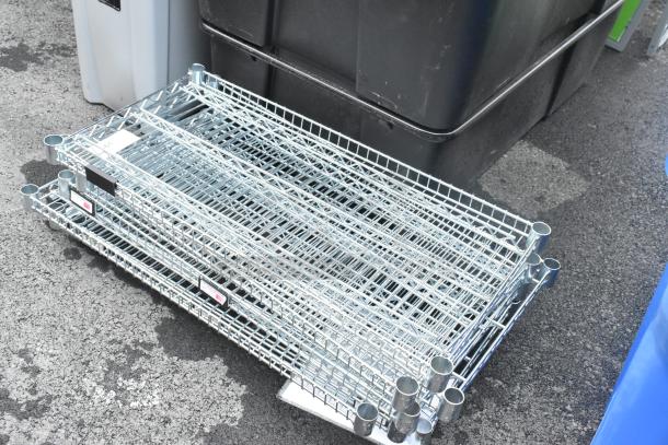 Lot of 11 chrome finish wire shelves, stacked. Durable condition with visible labels and mounting sockets. Ideal for storage.