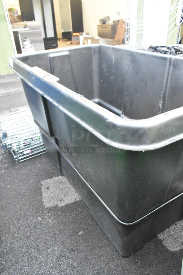 Black poly tilt truck, large capacity, durable plastic, used condition, ideal for industrial material transport.