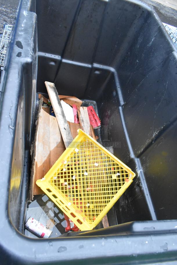 Black Poly Tilt Truck showing interior with various debris, including a yellow crate and cardboard. Good condition.