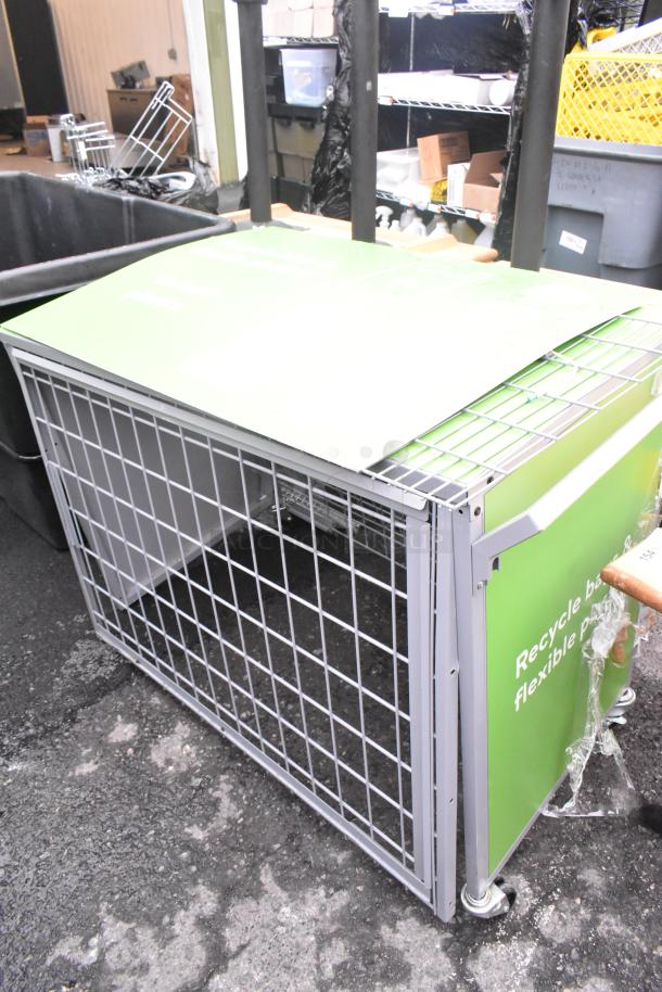 Gray metal cage with a green top panel, featuring a grid design. In good condition, suitable for storage or recycling.