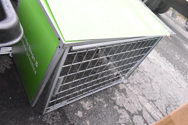 Gray metal cage with wire mesh sides, green top panel, and markings indicating recyclability. Appears in good condition.