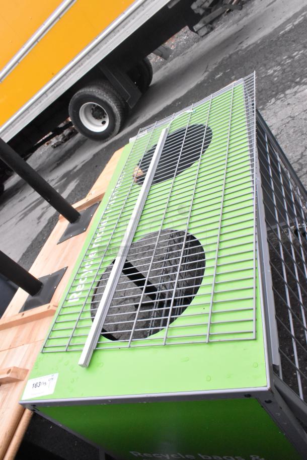 Gray metal cage with a green base featuring circular cutouts. A tag with "163" is visible. Condition appears sturdy.