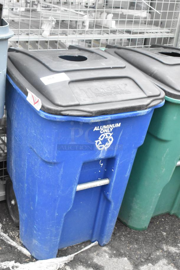 Two poly trash cans with hinge lids, blue and green. Blue can displays "Aluminum Only" marking. Used condition.
