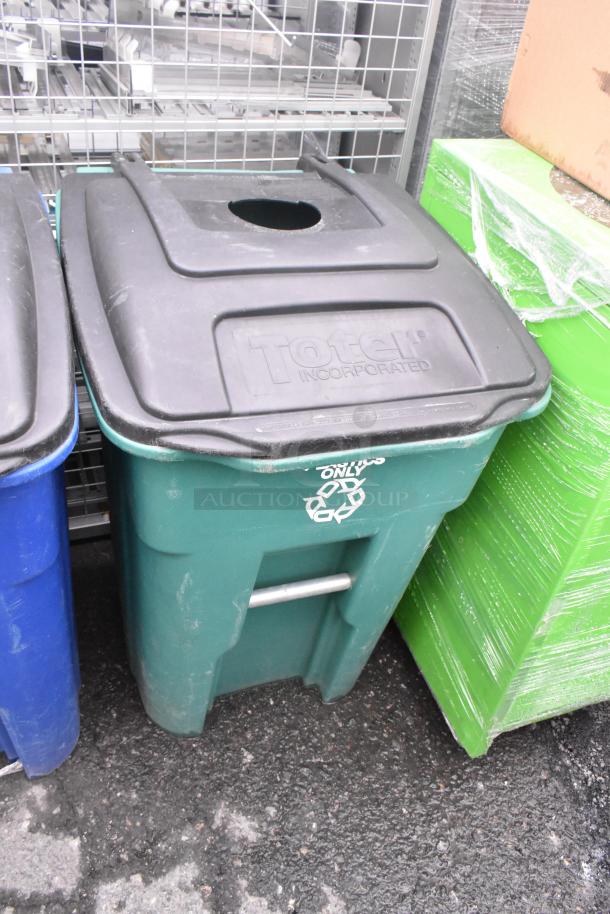 Two green Toter trash cans with hinged lids, labeled for recycling. Sturdy poly construction, slight wear visible.