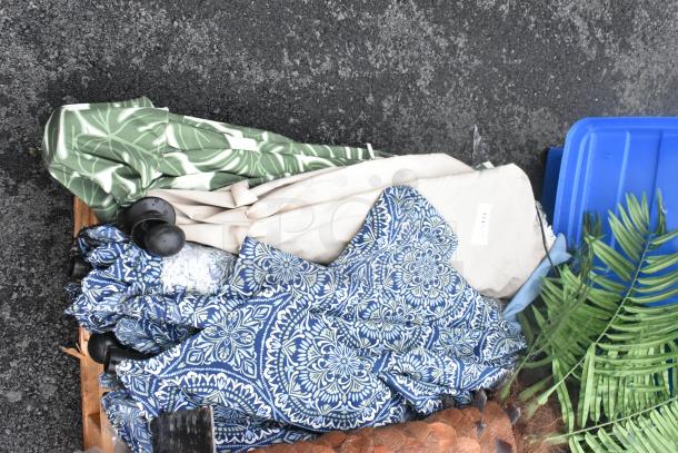 Assorted patio umbrellas and covers with various patterns and colors, including blue floral and green leaf designs. Condition appears mixed.