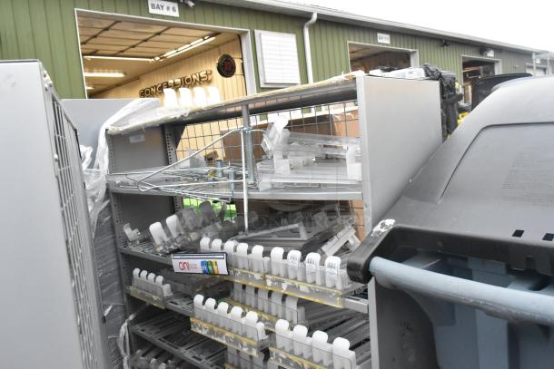Two gray metal shelving units with attached plastic shelving, visible wear, suitable for storage or retail.