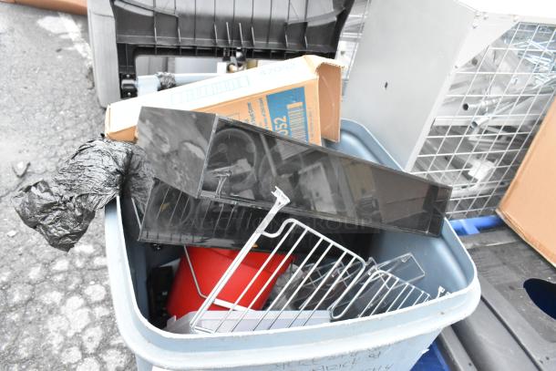 Gray poly trash can containing various items including a red bucket, metal rack, and cardboard box. Appears used.