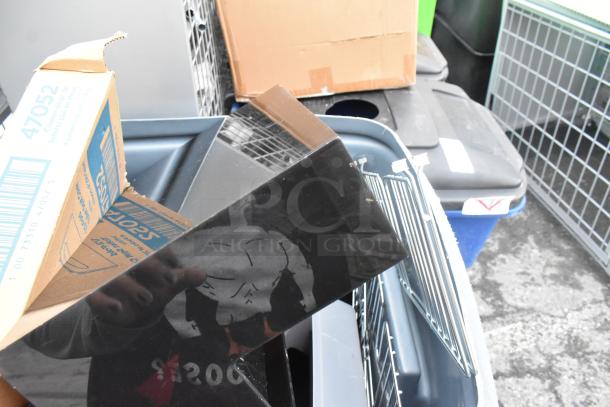 Gray poly trash can with a black lid, containing various items including a red bucket and cardboard box, in used condition.