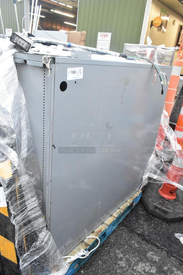 Two gray metal shelving units wrapped in plastic, slightly scratched. Includes wires and lockbox on top. Tag indicates auction lot "180."