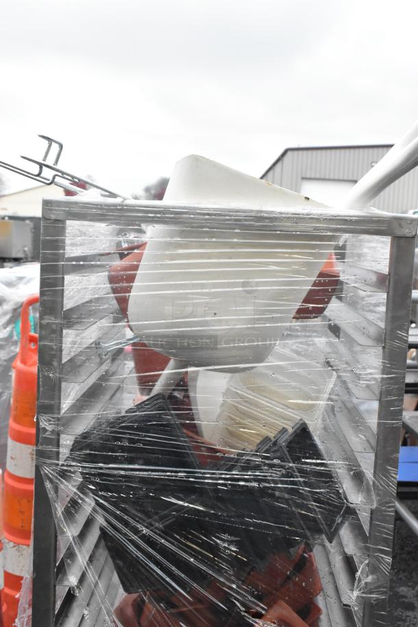 Metal commercial pan transport rack with multiple shelves on casters, covered in plastic wrap, used condition.