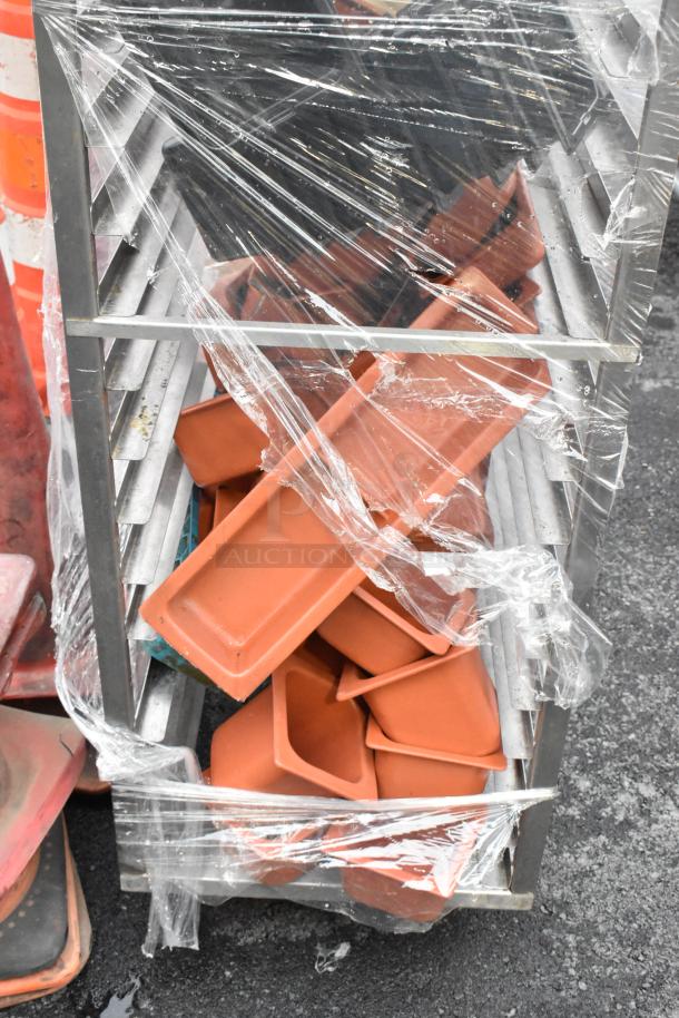 Metal commercial pan transport rack with multiple shelves, wrapped in plastic. Includes stackable red trays. Condition appears used.