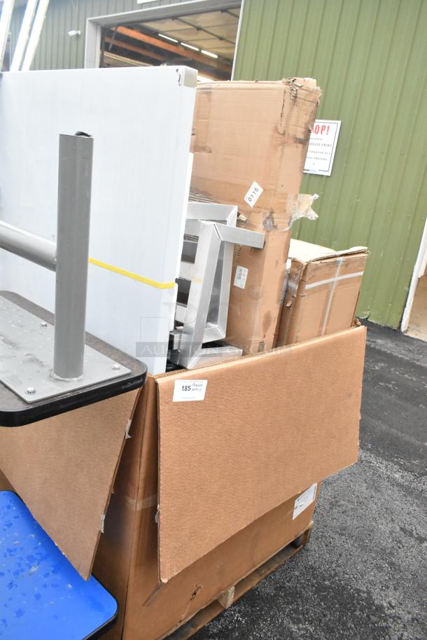 17 new scratch and dent items on a pallet, including parts of a tow-behind spreader and work table. Labels indicate lot 185.