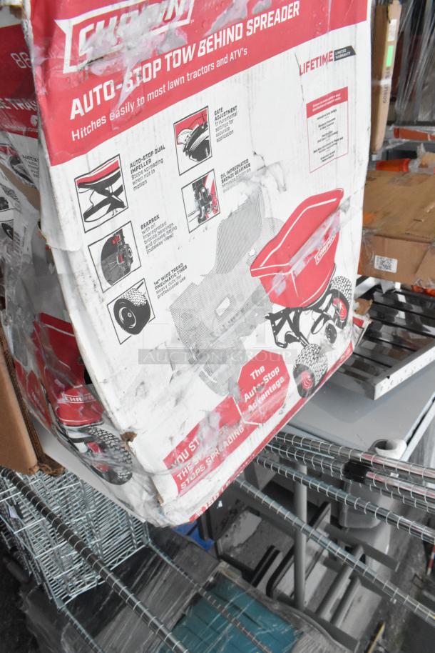 Box of Chion Auto-Stop Tow Behind Spreader, visibly damaged, label highlights features like gate adjustment and bronze bearings.