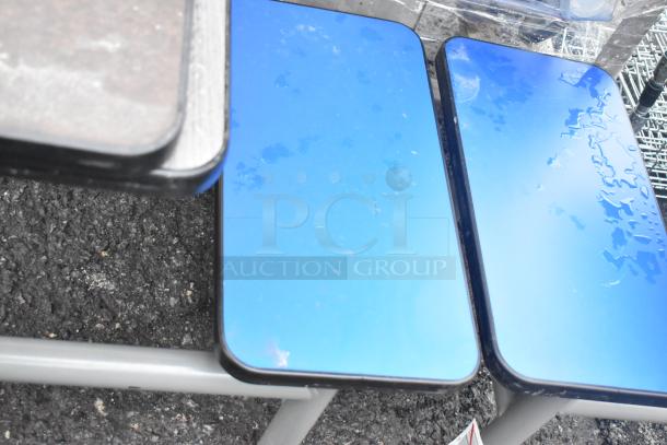 Metal table with two bench seats, reflective blue surfaces; modern design, minor wear. Auction lot includes four sets.