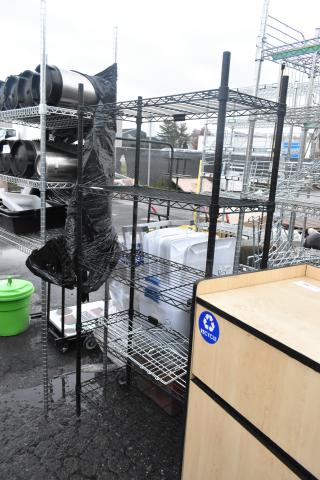 Black finish 4-tier wire shelving unit, used condition, buyer must dismantle, visible in an outdoor setting.