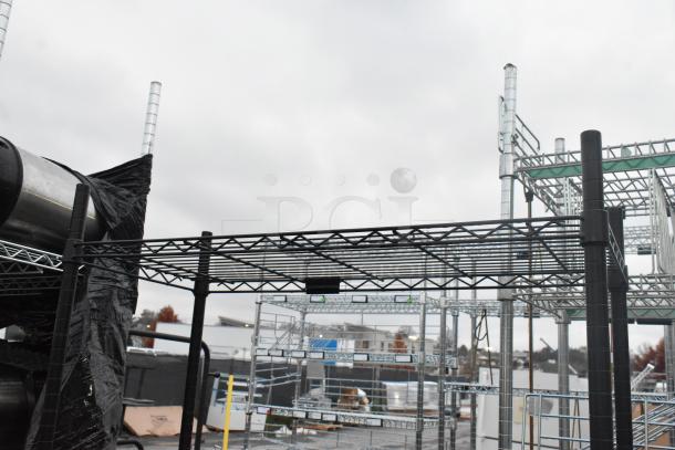 Black finish 4-tier wire shelving unit, sturdy metal, outdoor setting. Buyer to dismantle; consider freight charges.