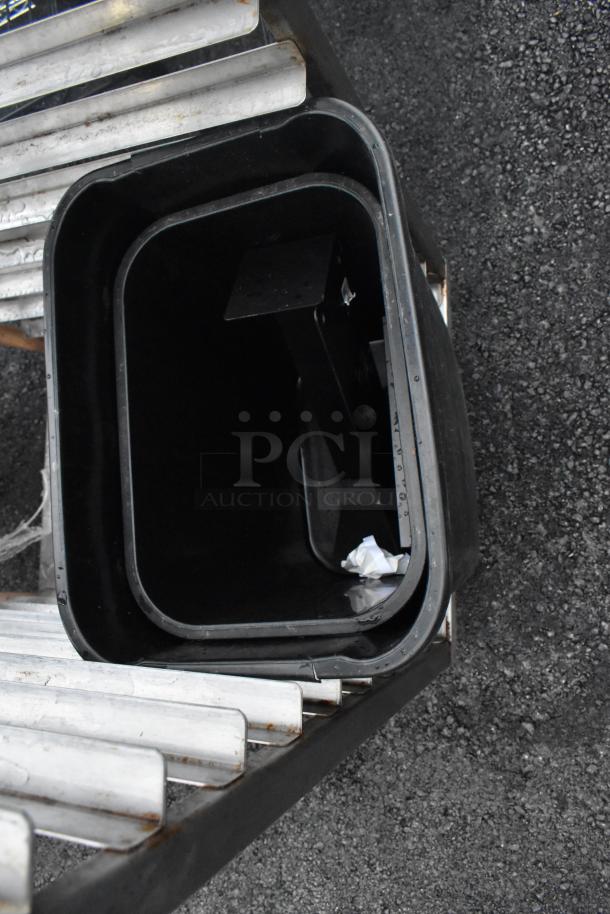 Metal commercial pan transport rack with casters, showing signs of use, featuring multiple shelves for pan storage.