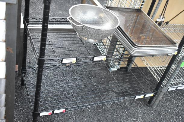 Black finish 6-tier wire shelving unit with trays and colander. Dismantling required, freight charges apply. Labels indicate shelf contents.