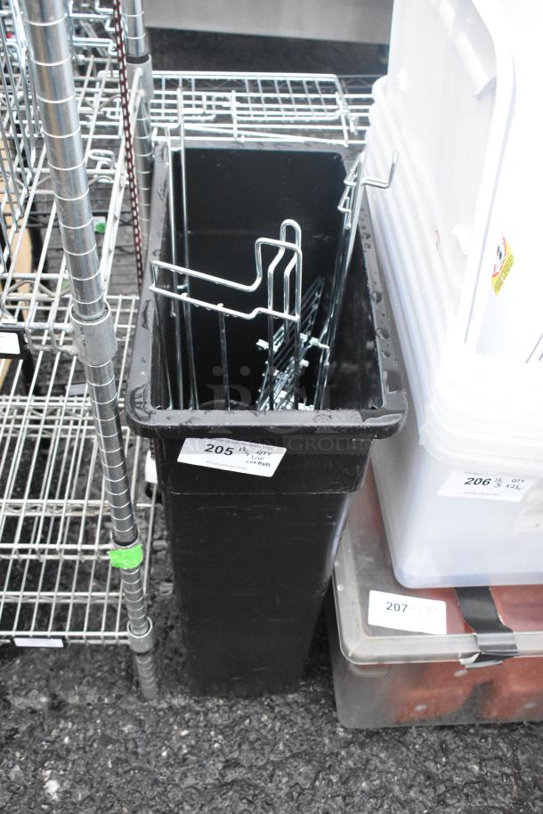 Black Poly Slim Jim trash can containing metal shelving parts, auction tag number 205, in good condition.