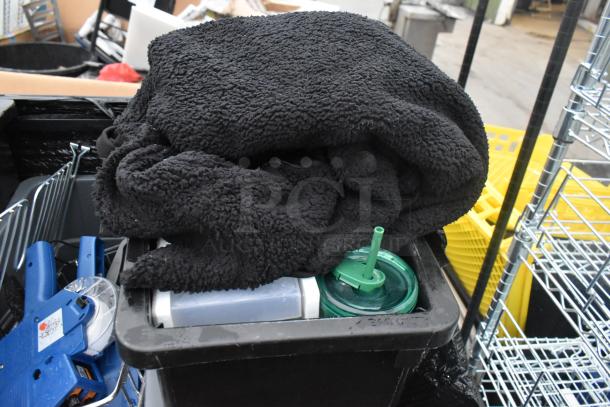 Three Slim Jim poly trash cans containing various items, including a black blanket and a green-lidded container.
