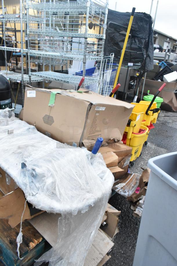 Five assorted new scratch and dent items, including a furniture dolly, wrapped in plastic. Boxes show minor wear.