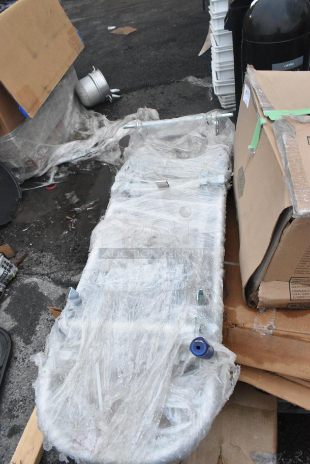 Five assorted new scratch and dent items, including a wrapped furniture dolly, in original packaging, shown from above.