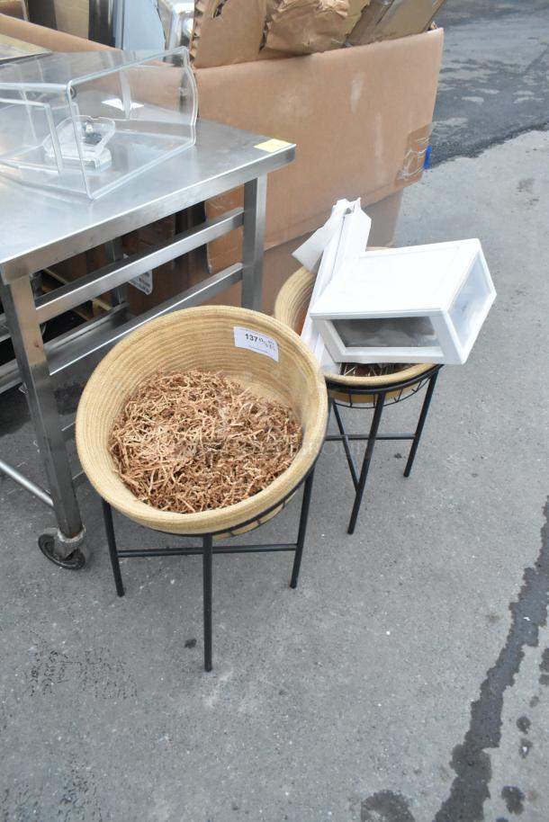 Two black metal basket stands holding straw, each with round wicker baskets. Auction tag visible, marked "137."